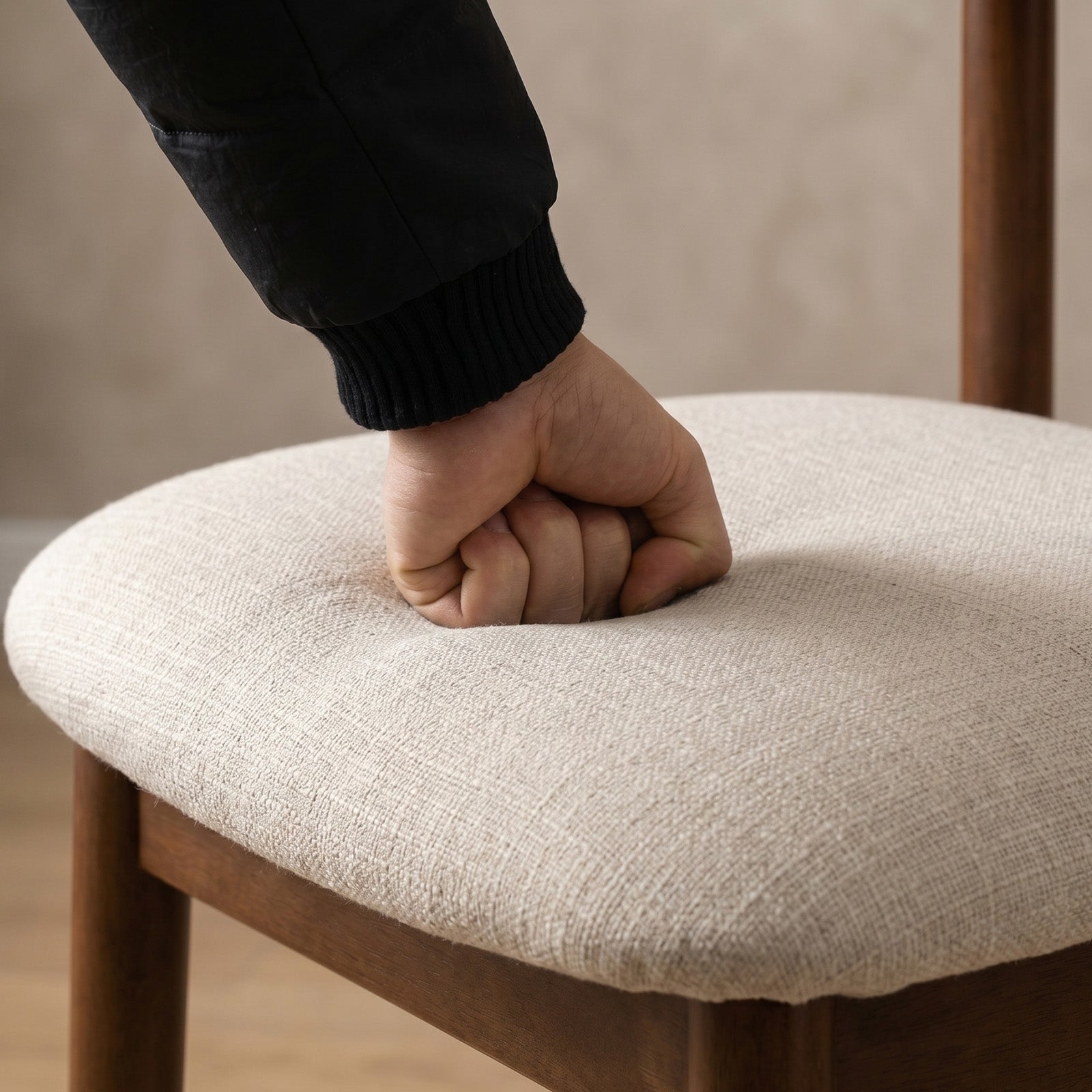 Hand resting on a chair seat with a blurred background